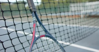 Tenis raketini ve topunu açık tenis kortunda kaleye yakın tut, ağır çekimde. Spor, rekabet, yaşam tarzı, eğlence ve etkinlik.