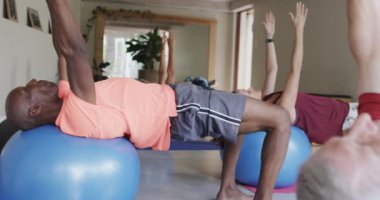 Farklı son sınıflar pilates sınıfında kadın koçla egzersiz toplarını yavaş çekimde kullanıyor. Egzersiz, emeklilik ve sağlıklı bir yaşam tarzı..