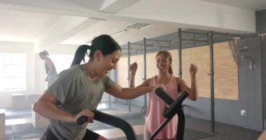 Değişmemiş farklı kadınlar, eliptik bisiklet eğitimi ve fitness sınıfında yavaş çekimde beşlik çakıyor. Sağlıklı yaşam tarzı, eğitim, motivasyon, güç, fitness ve egzersiz.