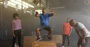 Çeşitli grup fitness sınıfı, erkek koçun boks yapmasını, spor salonunda ağır çekimde çapraz antrenman yapmasını izliyor. Sağlıklı yaşam tarzı, çapraz eğitim, fitness, motivasyon, güç ve egzersiz. 