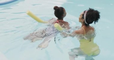 Mutlu Afro-Amerikan anne ve kızı bahçede yüzme havuzunda oynuyorlar, ağır çekimde. Yaşam tarzı, aile ve aile hayatı.