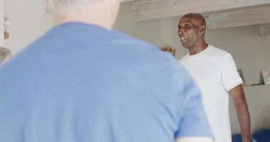 Ayakta duran ve erkek pilates koçunu dinleyen, değişmemiş, ağır çekimde mutlu yaşlılar. Egzersiz, emeklilik ve sağlıklı bir yaşam tarzı..