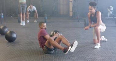 Çeşitli kadın koçlar, spor salonunda ağır çekimde tıp topuyla egzersiz yapan azimli erkekleri motive ediyor. Sağlıklı yaşam tarzı, çapraz eğitim, motivasyon, güç ve egzersiz.
