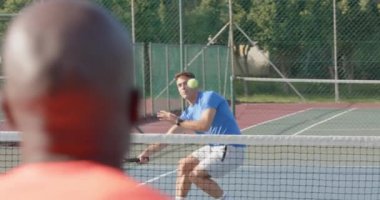 Açık hava tenis kortunda yavaş çekimde oynayan çeşitli erkek tenisçiler. Spor, rekabet, yaşam tarzı, eğlence ve etkinlik.