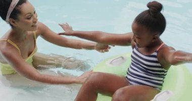 Mutlu Afro-Amerikan anne ve kızı bahçede yüzme havuzunda oynuyorlar, ağır çekimde. Yaşam tarzı, aile ve aile hayatı.