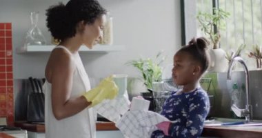 Mutlu Afro-Amerikan anne ve kızı mutfakta bulaşık yıkıyor, ağır çekimde. Yaşam tarzı, aile ve aile hayatı.