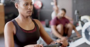 Odaklanmış Afro-Amerikan kadın spor salonunda kürek çekme eğitimi alıyor, ağır çekimde. Sağlıklı yaşam tarzı, çapraz eğitim, motivasyon, güç ve egzersiz.
