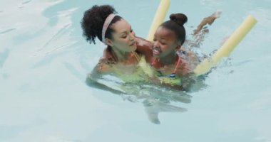 Mutlu Afro-Amerikan anne ve kızı bahçede yüzme havuzunda oynuyorlar, ağır çekimde. Yaşam tarzı, aile ve aile hayatı.