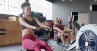 Odaklanmış Afro-Amerikan kadın spor salonunda kürek çekme eğitimi alıyor, ağır çekimde. Sağlıklı yaşam tarzı, çapraz eğitim, motivasyon, güç ve egzersiz.