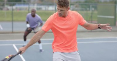 İki farklı erkek arkadaş sahada ağır çekimde çift top oynuyorlar. Spor, arkadaşlık, takım çalışması, eğlence, hafta sonu, yaşam tarzı ve etkinlik.