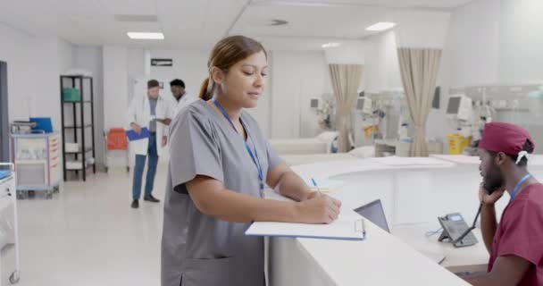 描述快乐多样的男护士和女护士慢吞吞地在接待处说话的形象 没有改变 医药和医院走廊 — 图库视频影像