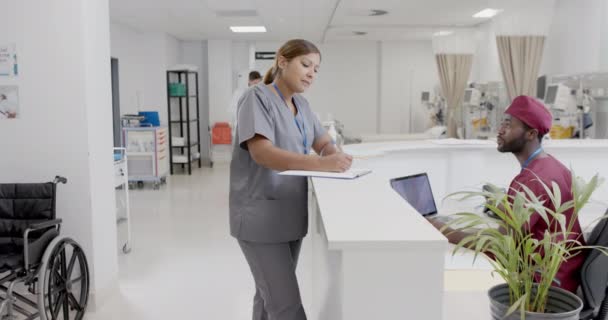 忙碌多样的男护士和女护士慢吞吞地在接待处说话 没有改变 医药和医院走廊 — 图库视频影像
