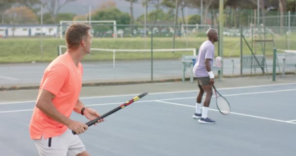 Két Különböző Férfi Barát Játszik Páros Visszatérő Labdát Szabadtéri Teniszpályán — Stock videók