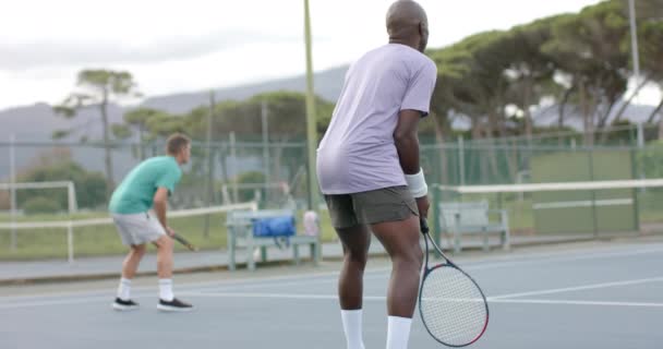 Forskjellige Mannlige Venner Som Spiller Double Retur Ball Utendørs Tennisbane – stockvideo