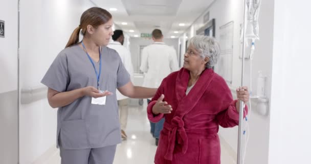 Σοβαρή Ποικιλόμορφη Νοσοκόμα Που Μιλάει Ανώτερους Ασθενείς Στάγδην Βάδιση Αργή — Αρχείο Βίντεο