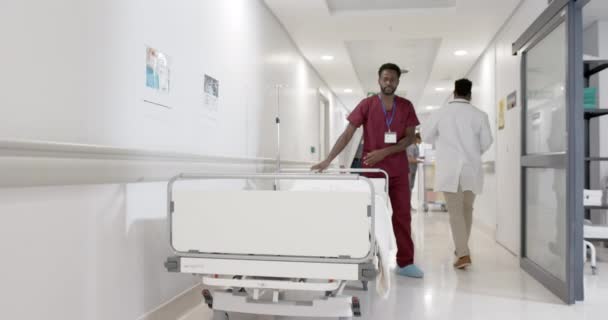 アフリカ系アメリカ人男性看護師に焦点を当て ゆっくりとした動きで病院のベッドで歩く 病院の廊下 — ストック動画