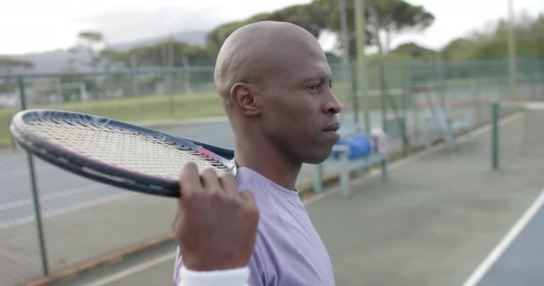 屋外コートでラケットを保持幸せなアフリカ系アメリカ人男性テニス選手の肖像画 スローモーション スポーツ ライフスタイル レジャー アクティビティ — ストック動画