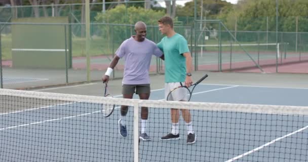Açık Havada Tenis Kortunda Birbirini Kucaklayan Iki Farklı Erkek Arkadaşın — Stok video
