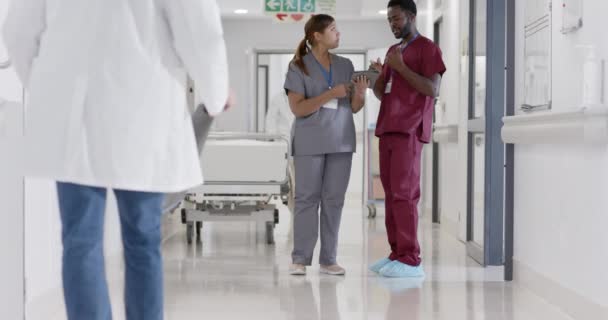 真剣な多様な男性と女性の看護師がゆっくりと話をし タブレットを使用しています 病院の廊下 — ストック動画