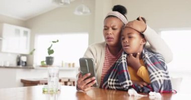 Değiştirilmemiş Afro-Amerikan anne ve hasta kız telefonlarını doktor görüntülü görüşmesi için kullanıyorlar. Yaşam tarzı, aile, sağlık, teletıp, iletişim ve ev hayatı.