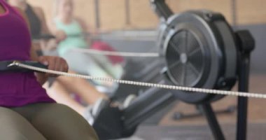 Yavaş çekimde spor salonunda kürek çeken değişmemiş farklı kadınlara odaklanmış. Sağlıklı yaşam tarzı, çapraz eğitim, motivasyon, güç, fitness ve egzersiz.