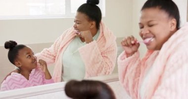Değiştirilmemiş Afro-Amerikan anne ve kızının dişlerini banyoda yavaş çekimde fırçalamaları. Yaşam tarzı, aile, kişisel bakım ve ev hayatı..