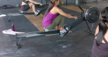 Yavaş çekimde spor salonunda kürek çeken değişmemiş farklı kadınlara odaklanmış. Sağlıklı yaşam tarzı, çapraz eğitim, motivasyon, güç, fitness ve egzersiz.