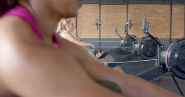 Yavaş çekimde spor salonunda kürek çeken değişmemiş farklı kadınlara odaklanmış. Sağlıklı yaşam tarzı, çapraz eğitim, motivasyon, güç, fitness ve egzersiz.