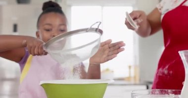 Değiştirilmemiş Afro-Amerikan anne ve kızı mutfakta yavaş çekimde yemek pişiriyor. Aşçılık, yaşam tarzı, aile, birliktelik ve aile hayatı..