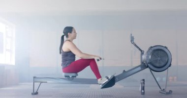 Kararlı, değişmemiş, çift ırklı kadın spor salonunda kürek çekiyor, ağır çekimde. Sağlıklı yaşam tarzı, çapraz eğitim, motivasyon, güç, fitness ve egzersiz.