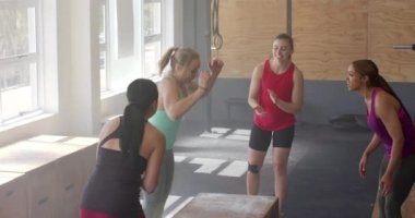 Değişmemiş farklı kadınlar azimli kadınları motive ediyor fitness sınıfında kutulara atlıyor, ağır çekimde. Sağlıklı yaşam tarzı, çapraz eğitim, motivasyon, güç, fitness ve egzersiz.