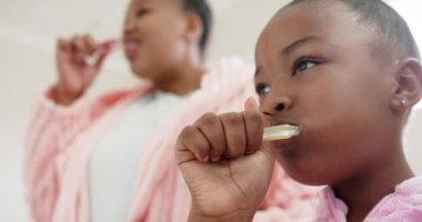 Değiştirilmemiş Afro-Amerikan anne ve kızının dişlerini banyoda yavaş çekimde fırçalamaları. Yaşam tarzı, aile, kişisel bakım ve ev hayatı..