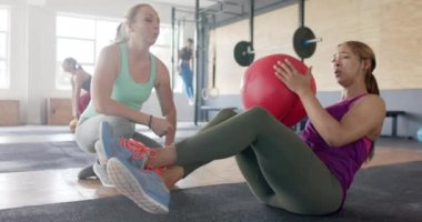 Değişmemiş farklı bir kadın, kararlı bir kadını spor salonunda tıp topu ile motive ediyor, ağır çekimde. Sağlıklı yaşam tarzı, çapraz eğitim, motivasyon, güç, fitness ve egzersiz.