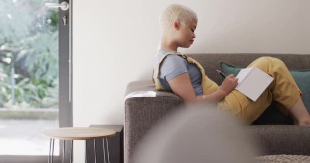 幸せな出産の女性がノートを取り スローモーションでソファに座っています 家庭生活 — ストック動画