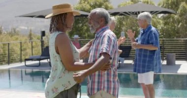 Mutlu kıdemli arkadaşlar güneşli bahçe partisinde yavaş çekimde konuşuyorlar ve dans ediyorlar. Arkadaşlık, yaz, eğlence, son sınıf yaşam tarzı, birliktelik ve kutlama..