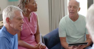 Grup terapisi seansında erkek terapistleri dinleyen farklı yaşlılar. Değiştirilmemiş, yavaş çekim. Yaşlılar yaşam tarzı, akıl sağlığı, arkadaşlık, destek ve grup terapisi.