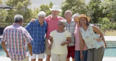 Güneşli bahçe partisinde değişmeden ağır çekimde kucaklaşan mutlu kıdemli arkadaşların portresi. Arkadaşlık, yaz, kıdemli yaşam tarzı, birliktelik ve kutlama..