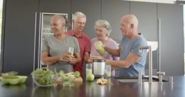 Mutfakta değişmeden, ağır çekimde sağlık içecekleri hazırlayan mutlu kıdemli arkadaşlar. Emeklilik, dostluk, kıdemli yaşam tarzı, beslenme, sağlık ve spor.