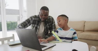 Mutlu Afro-Amerikan baba ve oğlu ağır çekimde dizüstü bilgisayar kullanıyor. Yaşam tarzı, aile, iletişim ve ev hayatı.