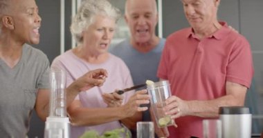 Mutfakta değişmeden, ağır çekimde sağlık içecekleri hazırlayan mutlu kıdemli arkadaşlar. Emeklilik, dostluk, kıdemli yaşam tarzı, beslenme, sağlık ve spor.