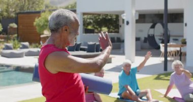Güneşli bahçede yoga grubuyla, değişmeden, ağır çekimde mutlu yaşlı adamın portresi. Emeklilik, yaz, arkadaşlık, yaşlılık yaşam tarzı, sağlık ve spor.