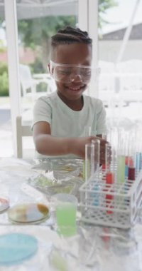 Afrika kökenli Amerikalı bir çocuğun test tüplerini ağır çekimde tutarken çekilmiş dikey videosu. Yaşam tarzı, çocukluk, bilim, eğitim ve ev hayatı.