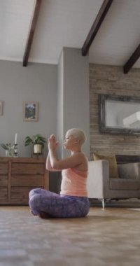 Evde yavaş çekimde meditasyon yapan mutlu melez kadının dikey videosu. Boş zaman, yaşam tarzı ve etkinlik.