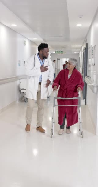 スローモーションで高齢女性患者と話をし 歩く多様な男性医師の垂直ビデオ — ストック動画