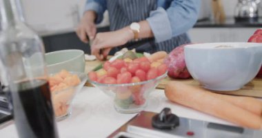Önlüklü, melez bir kadının yemek hazırlama, mutfakta sebze doğrama, ağır çekim. Yemek, yemek, sağlıklı yaşam ve ev hayatı..