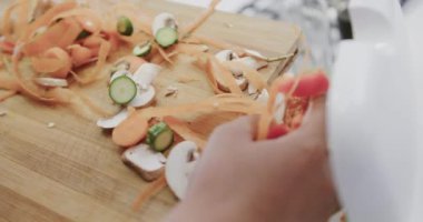 Mutfakta sebze atıkları taşıyan melez bir kadının elleri, ağır çekim. Yemek, yemek, sağlıklı yaşam, ekoloji, geri dönüşüm ve ev hayatı.