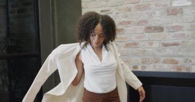 Çift ırklı mutlu iş kadını portresi ceket giyiyor ve kameraya gülümsüyor, yavaş çekim. İş, güven, ofis ve iş, değiştirilmemiş.