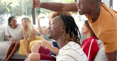 TV 'de spor seyreden ve yavaş çekimde beşlik çakan mutlu arkadaşlar. Spor, eğlence, boş zaman, arkadaşlık ve yaşam tarzı.