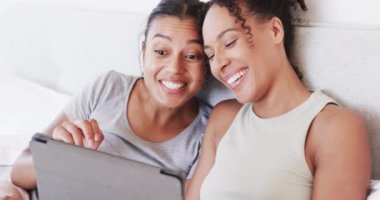 Çift ırklı mutlu lezbiyen çift yatakta tablet kullanıyor, konuşuyor ve sarılıyor, ağır çekimde. Yaşam tarzı, ilişki, birliktelik, rahatlama, iletişim, aşk ve ev hayatı, değişmemiş.