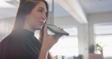 Kuafördeki beyaz kadın müşterimiz akıllı telefondan ağır çekimde konuşuyor. Yerel iş, iletişim, kuaförlük, saç bakımı ve kuaförlük, değiştirilmemiş.